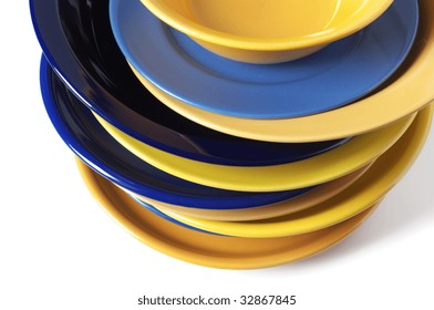 Stack of multicolored ceramic plates close-up on white background.