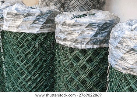 Stack of new chain-link wire mesh rolls at a construction site