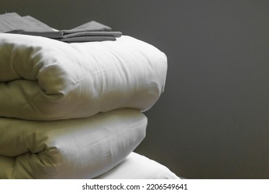 Stack of new clean bedding sheets soft folded blankets and pillows isolated on gray wall background indoors. Cleaning service in the hotel and rental apartments. Housekeeping and laundry concept. - Shutterstock ID 2206549641