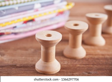 stack of of new fabrics in different colors cloth with empty wooden thread spools on the wooden table