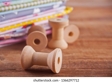 stack of of new fabrics in different colors cloth with empty wooden thread spools on the wooden table