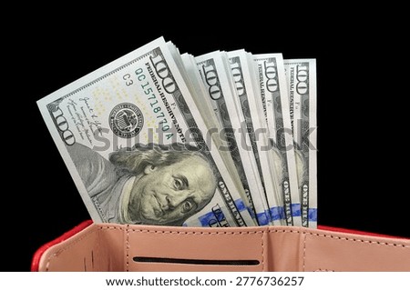 A stack of new hundred-dollar bills inside red leather wallet
