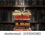 A stack of new study books on the table against the background of a bookshelf in library.