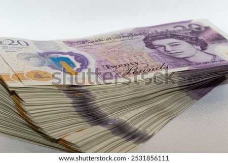 A stack of new twenty pound British banknotes arranged neatly, showcasing the portrait of Queen Elizabeth II and the Bank of England logo.