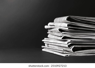Stack of newspapers in different languages on black background. Space for text