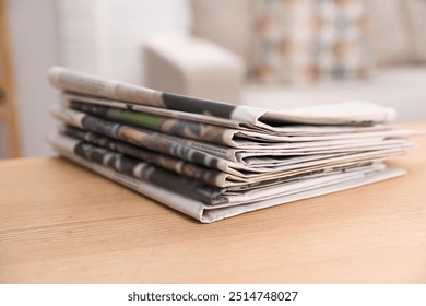 Stack of newspapers in different languages on table indoors