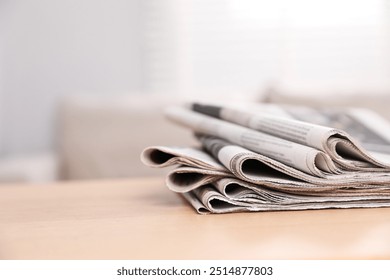 Stack of newspapers in different languages on table indoors. Space for text