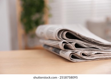 Stack of newspapers in different languages on table indoors, closeup