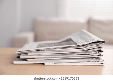 Stack of newspapers in different languages on table indoors
