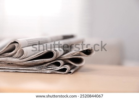 Stack of newspapers in different languages on table indoors. Space for text