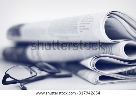 A stack of newspapers with glasses. Shallow depth of field.