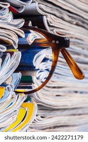 Stack of newspapers and magazines and reading glasses