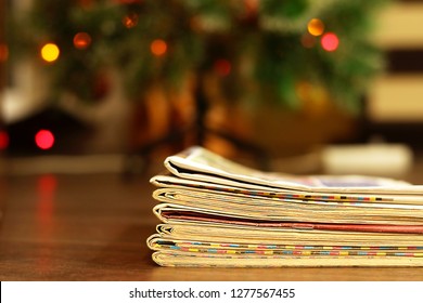 Stack of Newspapers and Magazines under Christmas Tree with Christmas Lights. Business Holiday Card with Copy Space