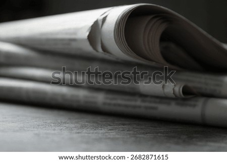 Stack of newspapers on grey table, closeup