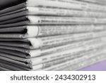 Stack of newspapers on light violet background, closeup. Journalist