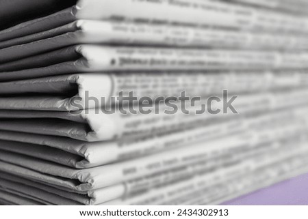 Stack of newspapers on light violet background, closeup. Journalist's work