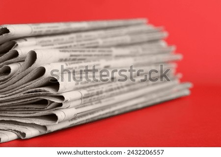 Stack of newspapers on red background, closeup. Journalist's work