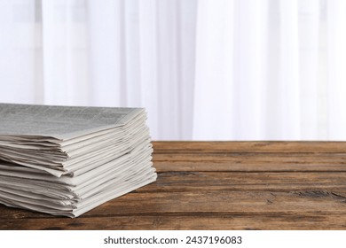 Stack of newspapers on wooden table, space for text. Journalist's work