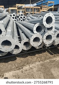 Stack of octagonal galvanized steel poles for street lighting or power distribution in a factory yard