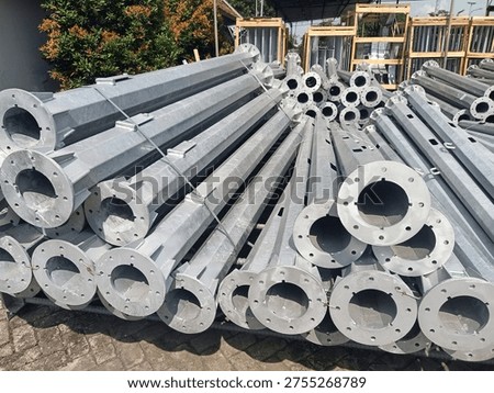 Stack of octagonal galvanized steel poles for street lighting or power distribution in a factory yard