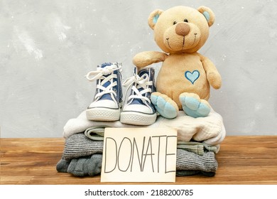 Stack Of Old Baby Children Clothes,teddy Bear Toys,sneakers Sorted Into Donate Categories.Donation,volunteering Help,humanitarian Aid.charity On Gray Background Still Life.Recycle Clothing,eco Cotton.