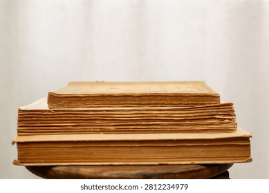A stack of old books. A collection of antique books neatly arranged on a wooden shelf against a white background. Conceptual themes of history, nostalgia, and old age. Retro style. 