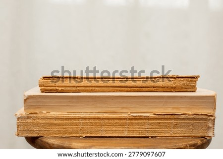A stack of old books. A collection of antique books neatly arranged on a wooden shelf against a white background. Conceptual themes of history, nostalgia, and old age. Retro style. High quality photo