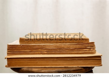 A stack of old books. A collection of antique books neatly arranged on a wooden shelf against a white background. Conceptual themes of history, nostalgia, and old age. Retro style. 