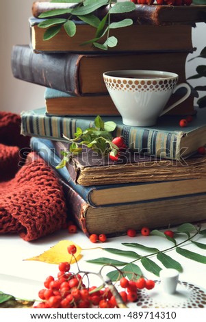 stack of old books, cup of tea and rowan berries. autumn Still Life