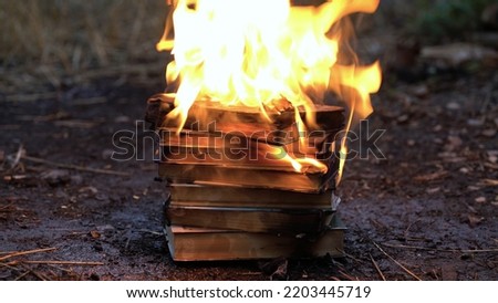 A stack of old books on fire burns on the ground.