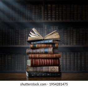A stack of old books on table against background of bookshelf in library. Ancient books as a symbol of knowledge, history, memory and information. Conceptual background on education, literature topics - Shutterstock ID 1954281475