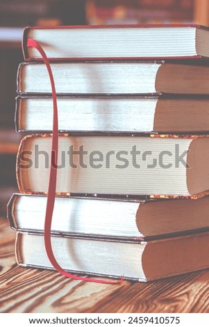 A stack of old books on table against background of bookshelf in library. Conceptual background on education, literature topics