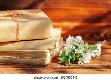 A Stack Of Old Books On A Wooden Background With A Sprig Of A Flowering Tree. The Concept Of Memorabilia And Historical Notes