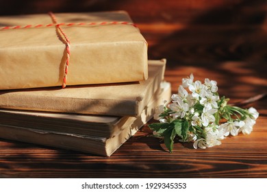 A Stack Of Old Books On A Wooden Background With A Sprig Of A Flowering Tree. The Concept Of Memorabilia And Historical Notes