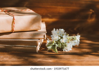 A Stack Of Old Books On A Wooden Background With A Sprig Of A Flowering Tree. The Concept Of Memorabilia And Historical Notes