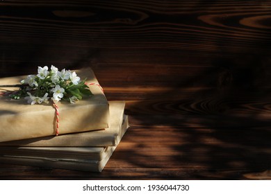 A Stack Of Old Books On A Wooden Background With A Sprig Of A Flowering Tree. The Concept Of Memorabilia And Historical Notes