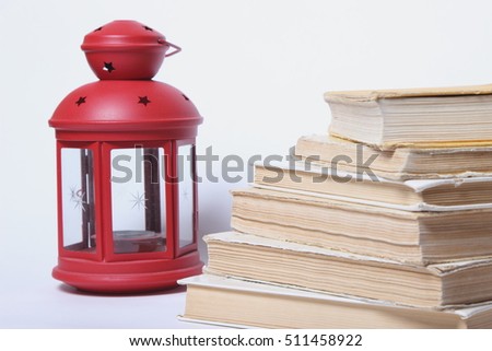 stack of old books. red lamp with candle on white background
