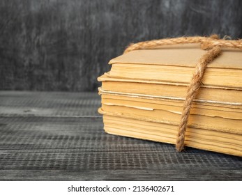 A stack of old books tied with a rope on a wooden background.Education and learning.