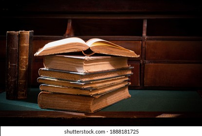 A stack of old books. Vintage book on wooden table. Magic lightning around a glowing book in the room of darkness. Selective focus - Powered by Shutterstock