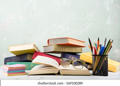 A Stack Of Old Color Books, Glasses, Stationery On A Table And A Green Background