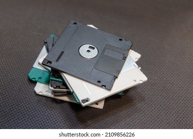 stack of old floppy disks stacked on a table, obsolete disk media