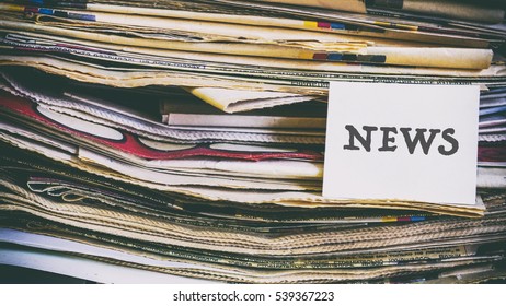 A stack of old newspapers, words on a paper sticker next
