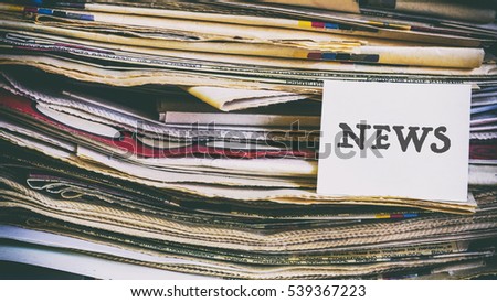 A stack of old newspapers, words on a paper sticker next