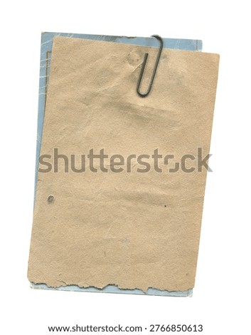 Stack of old paper tags clipped together with a metal paper clip showing worn edges and aged texture isolated on a white background