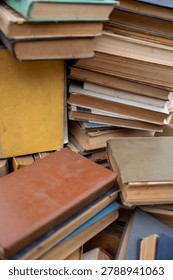 Stack of old secondhand books in hardcover and paperback with worn pages and covers, vintage literature on display at flea market or garage sale.