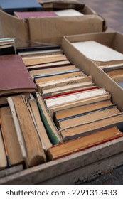 Stack of old secondhand books in hardcover and paperback with worn pages and covers, vintage literature on display at flea market or garage sale.