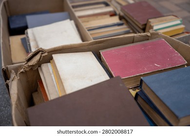 Stack of old secondhand books in hardcover and paperback with worn pages and covers, vintage literature on display at flea market or garage sale.
