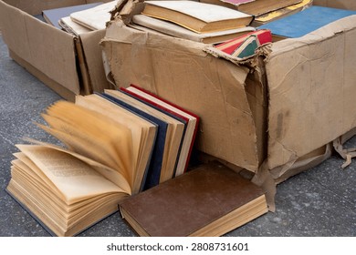 Stack of old secondhand books in hardcover and paperback with worn pages and covers, vintage literature on display at flea market or garage sale.