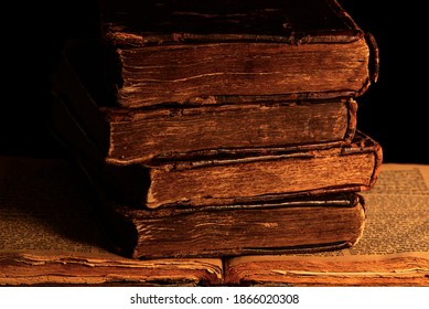 Stack of old shabby Jewish books in leather binding on the open pages of Machzor in the dark. Closeup. Low key