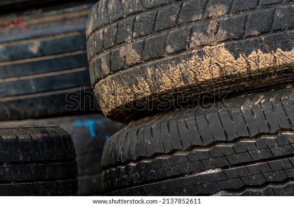 Stack of old tires. Pile of used tires. Black\
rubber tire of car. Dirty used tyres. Closeup old tyres waste for\
recycle. Closeup tread of an old dirty tyre. Change car tire for\
safety concept.